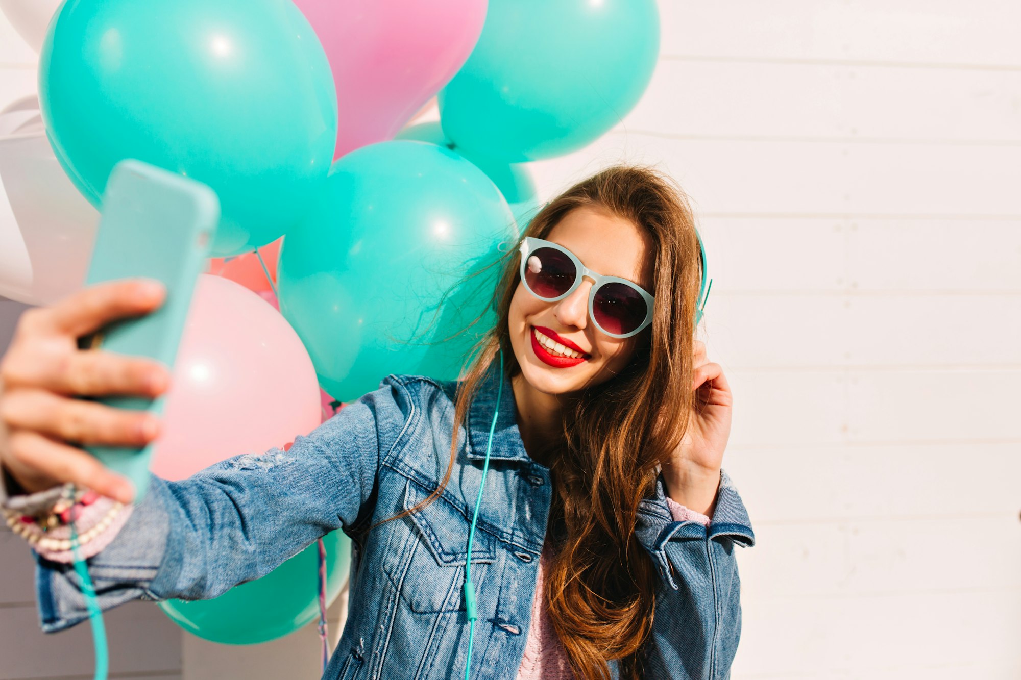 Adorable young woman with long hair makes new photo for facebook profile while having fun at friend'