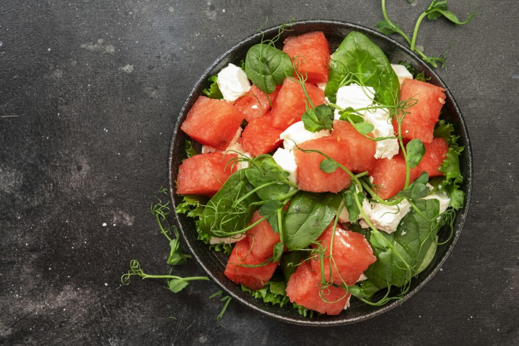 Summer watermelon salad bowl with goat cheese, spinach and pea sprouts