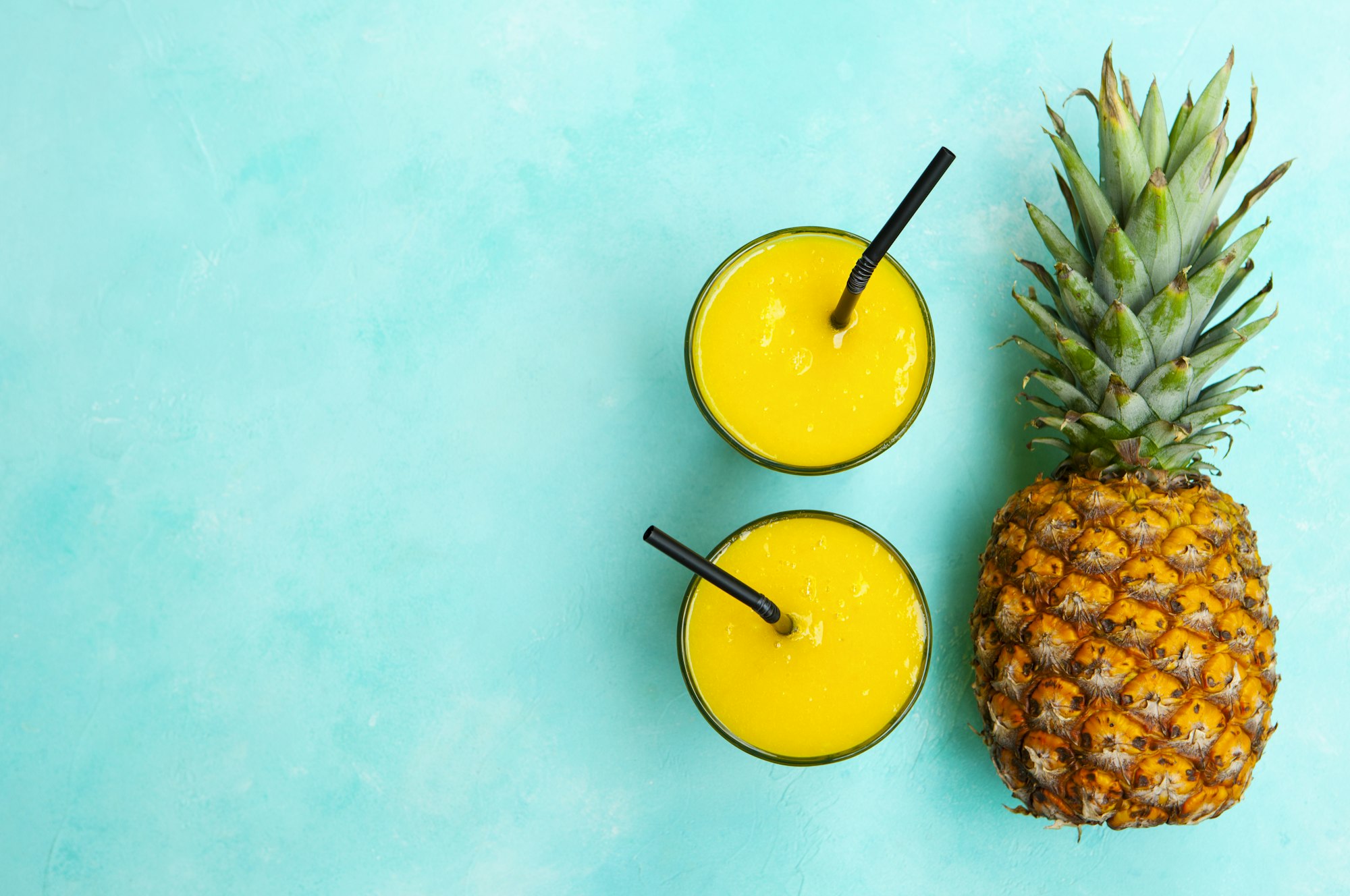 Pineapple with Tropical Fresh Juice, Smoothie on Blue Background. Copy Space. Top View